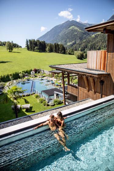Paar entspannt im Outdoor Pool mit Blick auf die Sürdtiroler Alpen