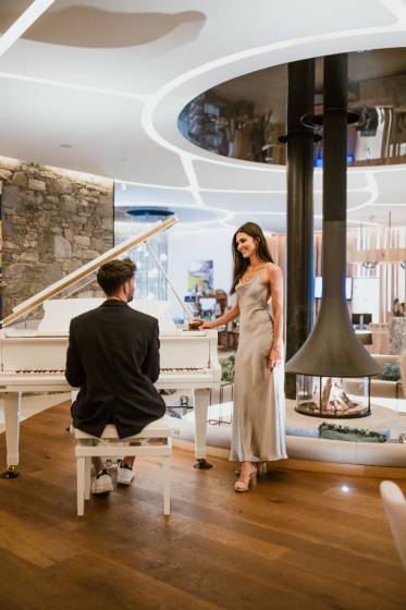 Mann sitzt am Klavier, Frau steht daneben in Lobby der Golf Lodge