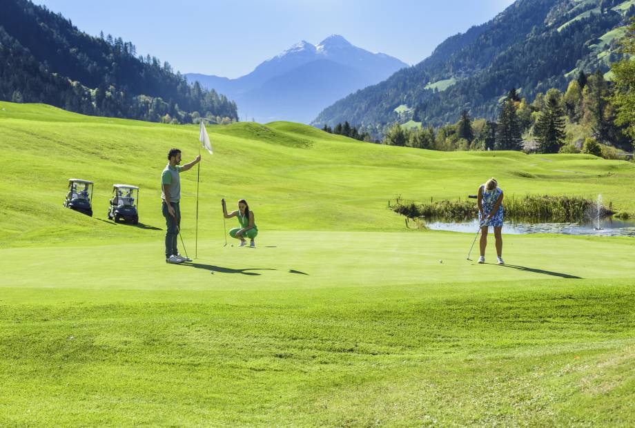 Golfer in der Sonne auf dem Green mit Blick auf die Alpen
